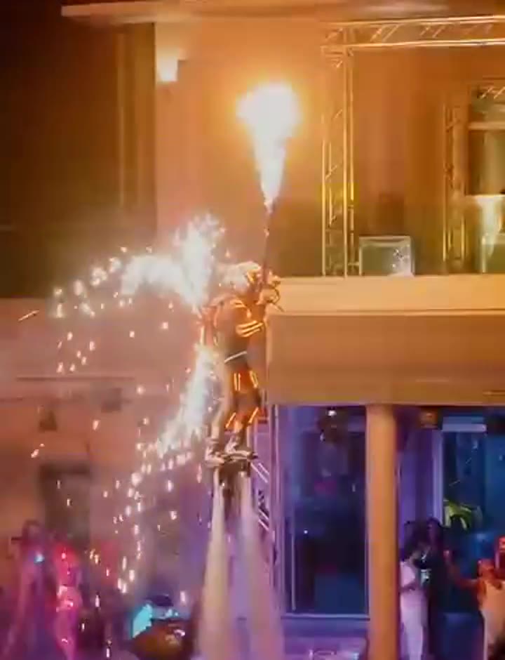 Close LED flyboard fire set over a private Phuket pool, spark wings and guests on the deck