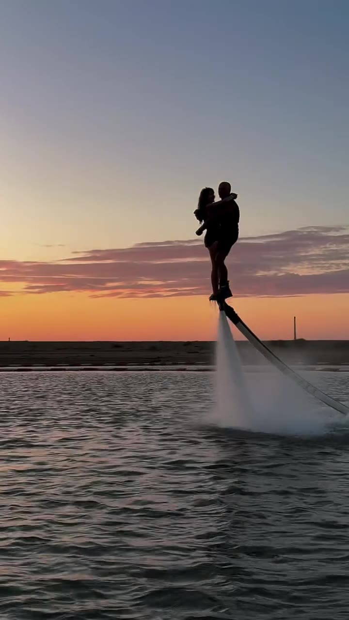 Sunset tandem flyboard lesson: couple hovering over the lagoon as Valerii teaches the first flight