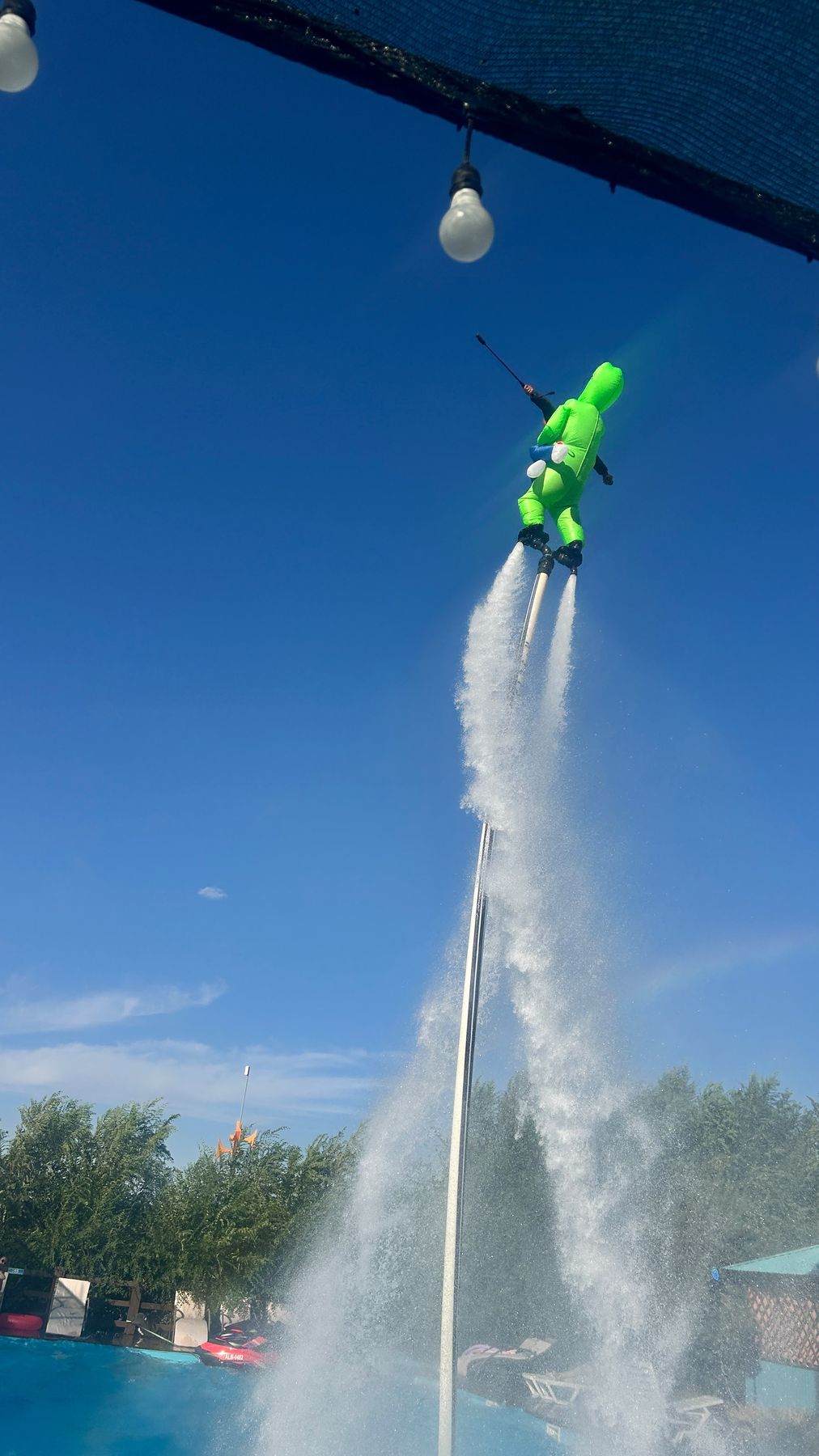 Flyboard character costume climbing a water column against blue sky